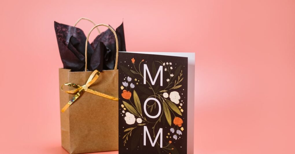 A stylish Mother's Day gift bag and card set with floral design on a pink background.