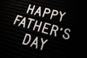Close-up of 'Happy Father's Day' text in white letters on a black textured background.