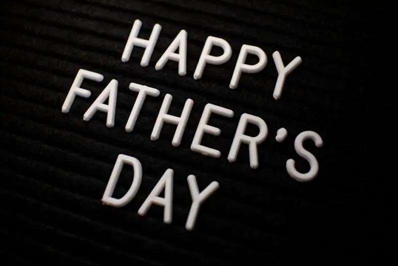 Close-up of 'Happy Father's Day' text in white letters on a black textured background.